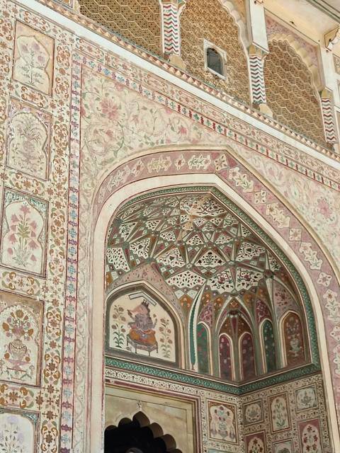       Vibrant frescoed archway with floral and geometric motifs in pastel hues inside Amber Fort.
  