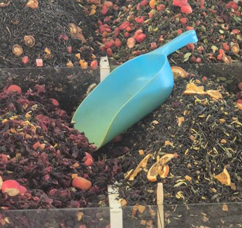      Close-up of loose tea and dried fruit mixture with a blue plastic scoop.
  
