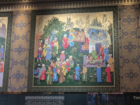       Colorful historic mural depicting a royal court scene on an ornately patterned wall.
  