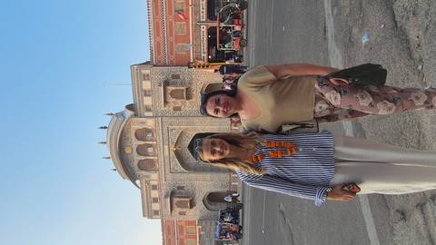       Two travellers in front of the ornately painted entrance gate of Jaipur’s City Palace complex.
  