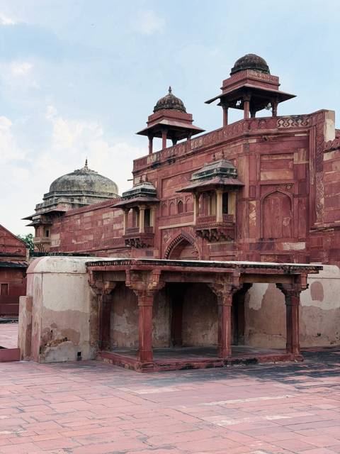      Detailed red-sandstone Mughal architecture featuring domes, arches, and ornate balconies.
  