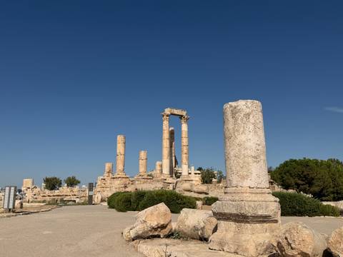       Ancient columns of the Temple of Hercules rise above the ruins of Amman Citadel under a clear blue sky.
  