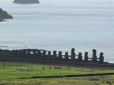       Distant line of moai statues at Ahu Tongariki stand against the vast Pacific backdrop.
  