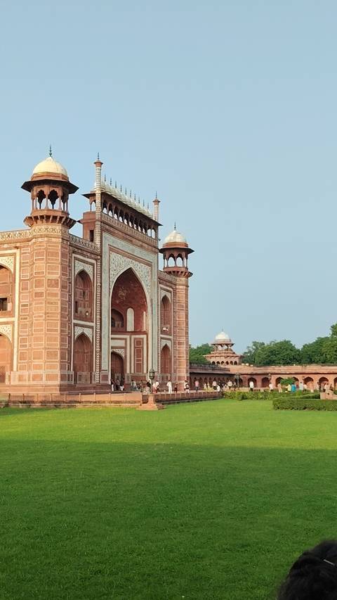       The grand sandstone gateway to the Taj Mahal complex with visitors gathered below.
  