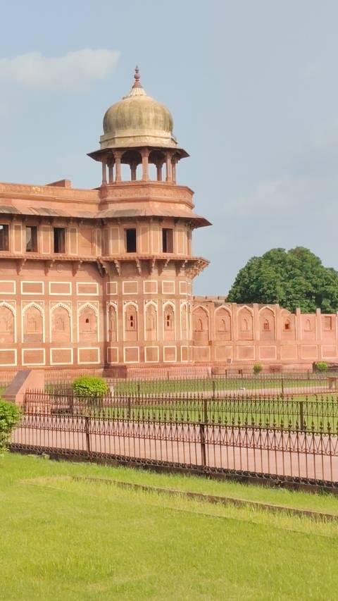       Close-up of ornate red sandstone walls and domed bastion of a Mughal fort.
  