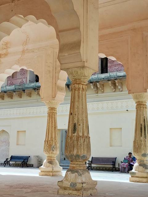       Weathered sandstone columns with intricate capitals inside an Indian palace courtyard.
  