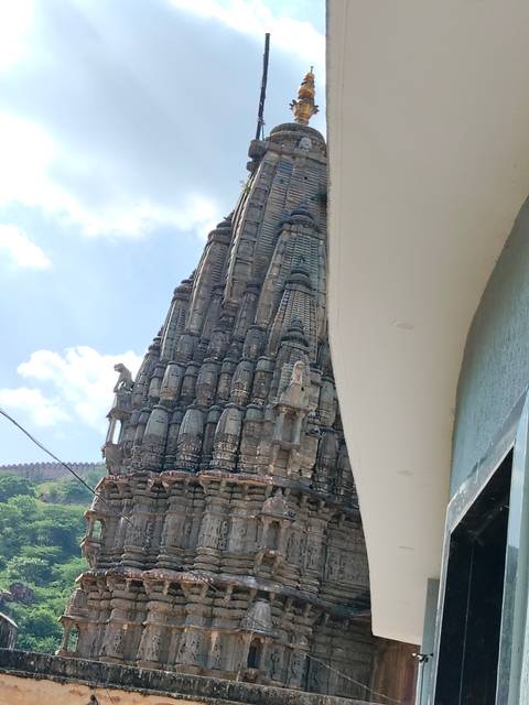       Stone temple spire rises beside a modern white façade under a bright sky.
  