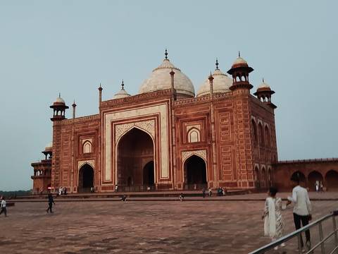       Side mosque within the Taj Mahal complex set in an open courtyard with scattered visitors.
  