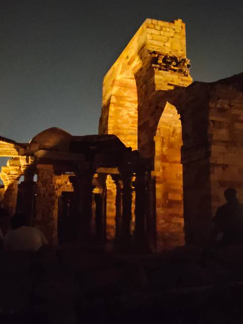       Dark, grainy night scene of ancient stone arches and pillars with minimal lighting.
  