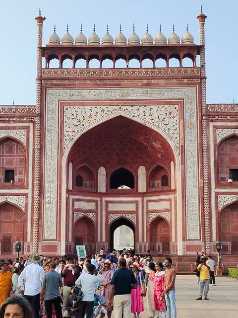       Detailed façade of the Taj Mahal gateway showcasing red sandstone and white floral inlay.
  