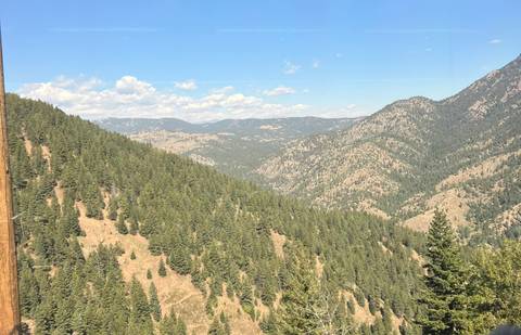       Expansive view across forested mountain ridges under clear blue sky
  