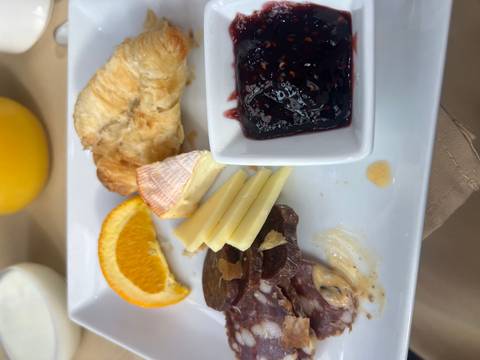       Breakfast plate with croissant, cheeses, orange slice, cured meat and berry jam
  