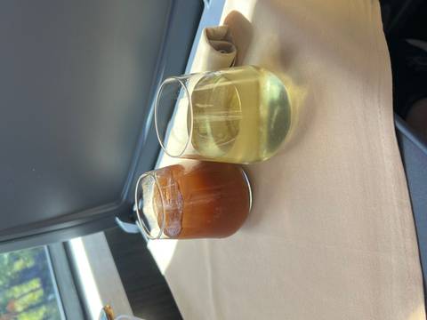       Two beverage glasses, one iced coffee and one white wine, on a table by a train window
  