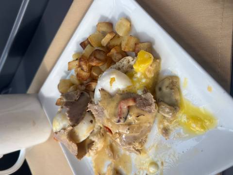       Eggs benedict style breakfast with diced potatoes on a white plate
  