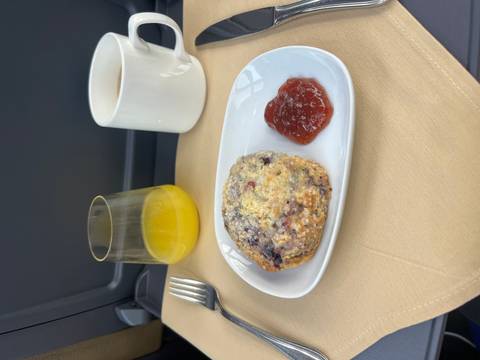       Scone with fruit jam served alongside orange juice and coffee on a train table
  