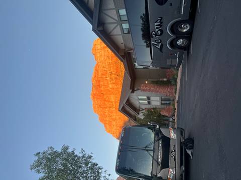       Red rock formation glowing in sunset light behind hotel buildings and tour buses
  
