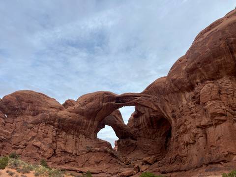       Impressive natural stone arch formations rising against an overcast sky in a desert canyon.
  