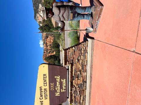       Visitor center sign for Dixie National Forest with a Smokey Bear statue beside it.
  