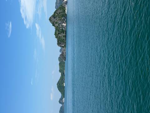      Expansive turquoise bay with calm water and forest-covered limestone islands under a clear blue sky.
  