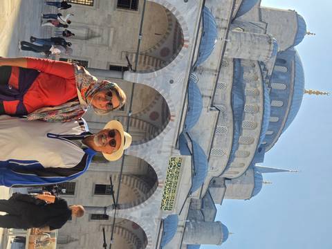       Smiling couple pose in front of the domes and minarets of Istanbul's Blue Mosque.
  