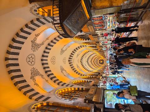       Bustling interior of Istanbul’s Spice Bazaar with ornate vaulted ceiling and rows of colorful goods.
  
