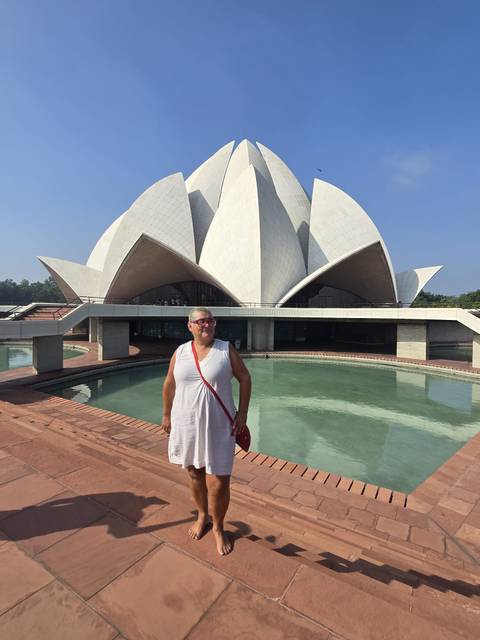       Woman poses beside the reflecting pool before the white lotus-shaped Baháʼí House of Worship in Delhi.
  