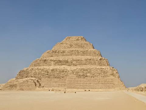       The Step Pyramid of Djoser rises in layers of weathered stone against a cloudless desert sky.
  