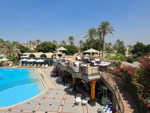       Luxury resort pool with palm-lined terraces, cabanas and bright blue water under a clear sky.
  