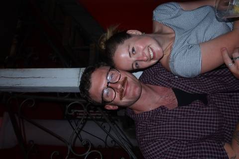       Close-up nighttime portrait of a smiling couple inside a dimly lit restaurant stairwell.
  