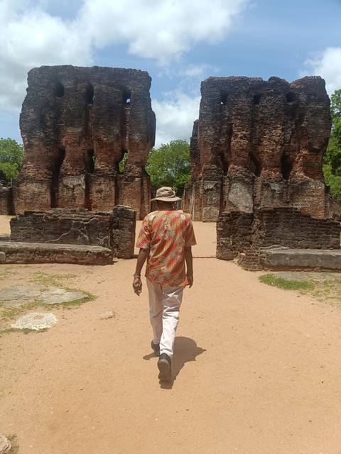       Guide walks through ancient brick ruins with weathered columns and arches.
  