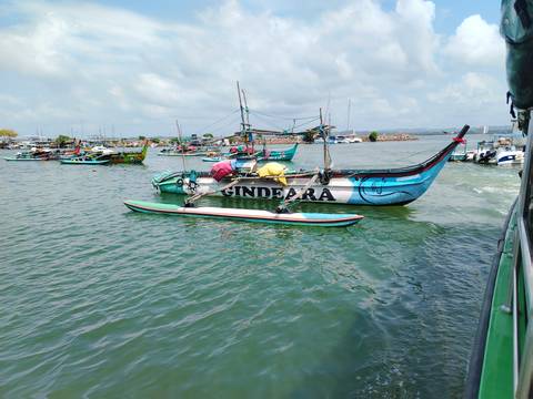       Colorful fishing boats anchored in a calm harbour under a partly cloudy sky.
  