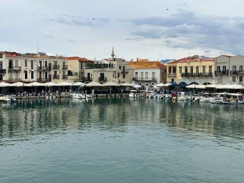      Picturesque Venetian harbor lined with pastel buildings reflecting in calm water under a mottled sky.
  