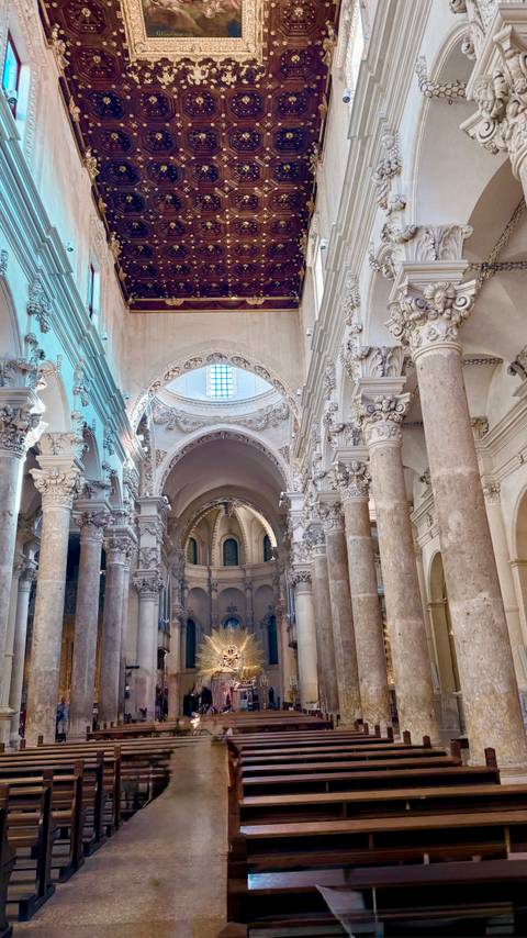       Ornate baroque columns and vaulted arches inside a grand Italian cathedral.
  