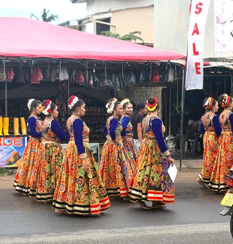       A procession of Sri Lankan women in brightly patterned traditional costumes prepares for a cultural performance.
  