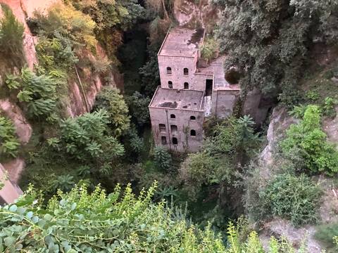       Ruins of an old mill nestled deep in a lush green ravine.
  