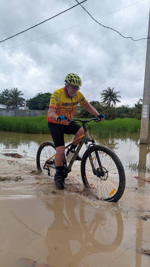       Cyclist rides through a flooded path with rice paddies and palm trees around.
  