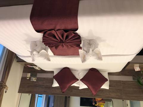       Hotel bed neatly made with folded towel elephants and burgundy accents.
  