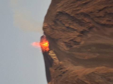       Blurry close-up of fiery lava erupting from the crater of Stromboli at dusk.
  