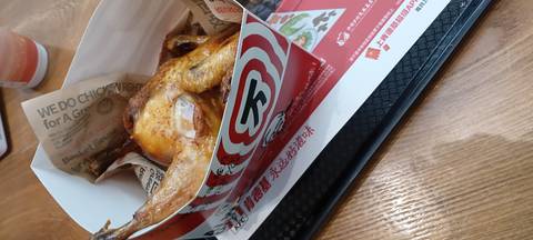      Fast-food style roasted chicken served in a branded paper box on a cafeteria tray.
  