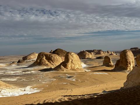       Wide view of wind-sculpted chalk towers and sandy basins dusted with white mineral deposits.
  