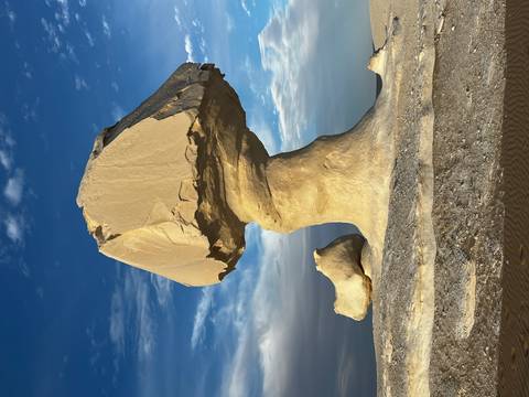       Tall lone chalk pillar shaped like a mushroom stem stands against deep blue sky.
  