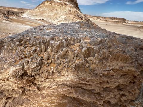       Close-up of jagged crystal formations embedded in a rock outcrop in the desert.
  