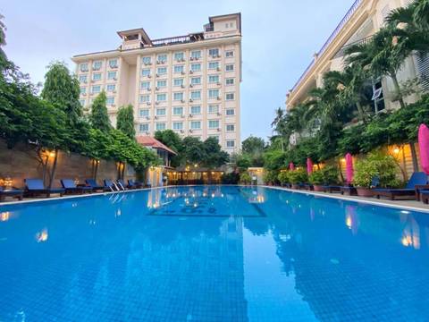      Inviting hotel pool surrounded by lush greenery and multi-storey accommodation blocks.
  