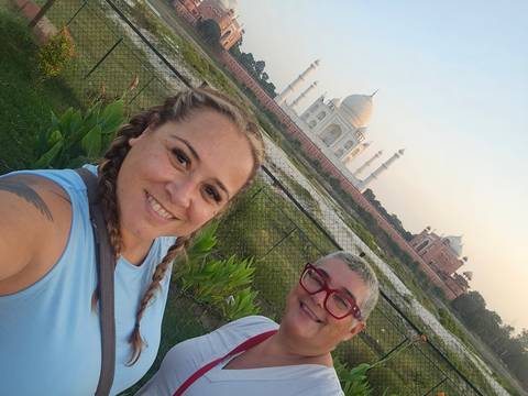       Selfie of two travellers in front of the Taj Mahal at soft evening light from riverside garden
  