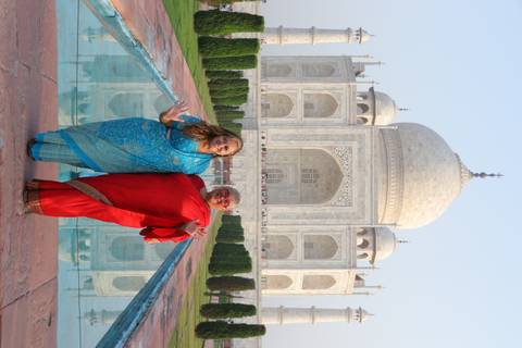       Two women dressed in colourful saris stand on the long reflecting pool axis leading to the Taj Mahal
  
