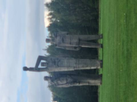       Three large concrete Soviet-era statues standing in a grassy park.
  