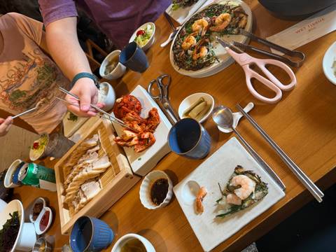       Traditional Korean meal with kimchi and pork being served at a wooden table.
  