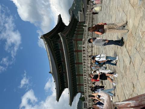       Visitors walk across the courtyard of Gyeongbokgung Palace on a sunny day.
  