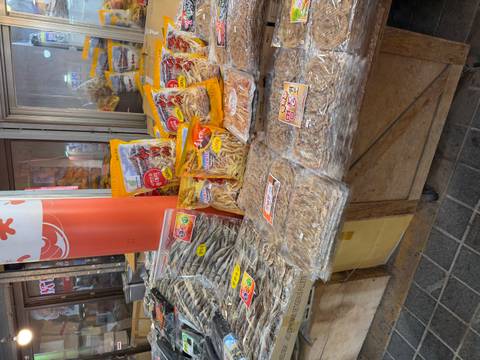       Assortment of dried fish and seafood snacks packaged for sale at an indoor market stall.
  