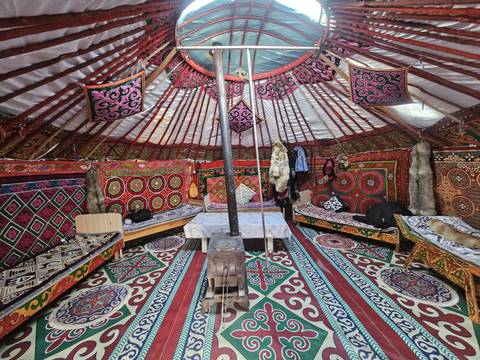       Color-saturated interior of a Kazakh ger decorated with patterned carpets, tapestries and saddles.
  